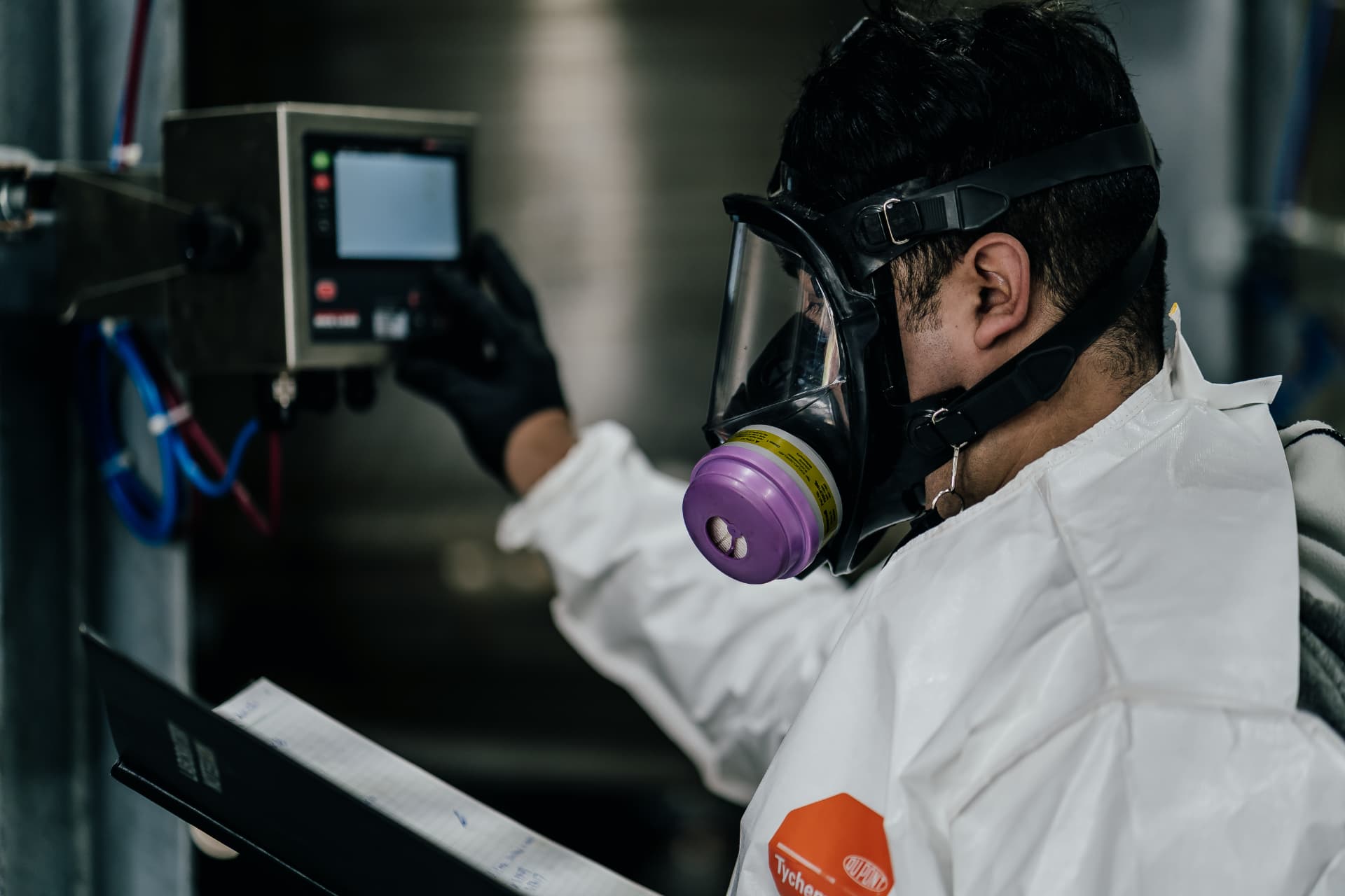 Element Chemicals technician in protective equipment reviewing process controls